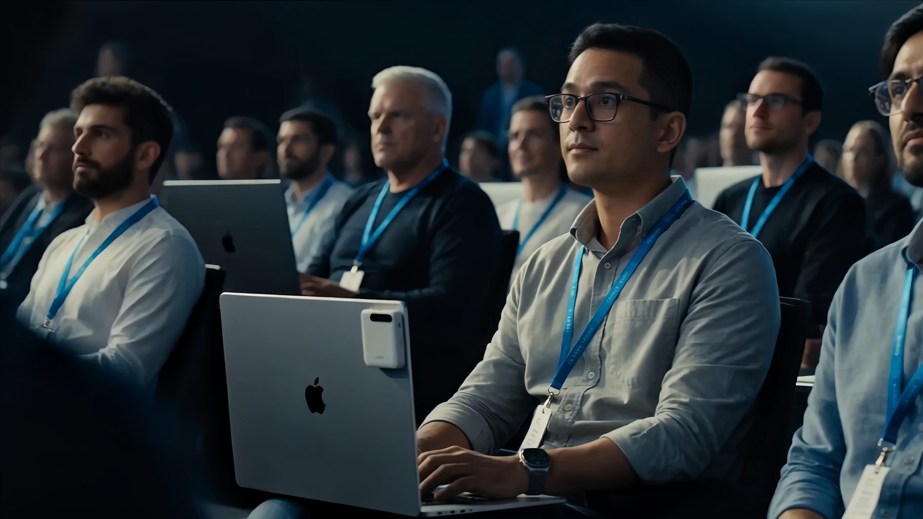 A seated conference audience wearing badges, a laptop in front with the A2 Pro on its lid